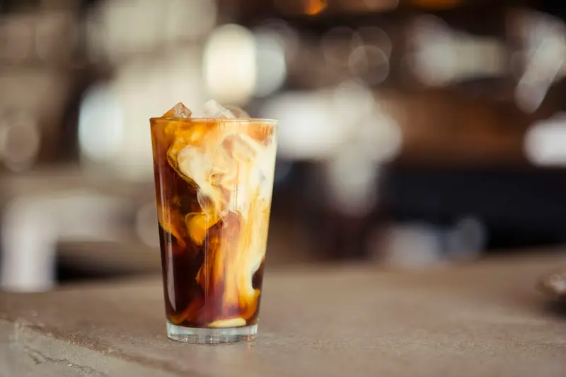 Iced coffee in a tall glass catching the window light