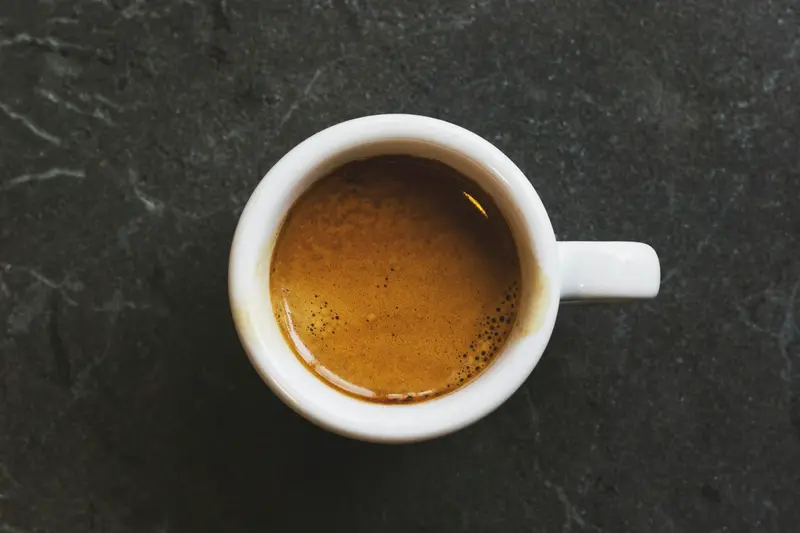 A cup of espresso with thick crema on a dark slate table
