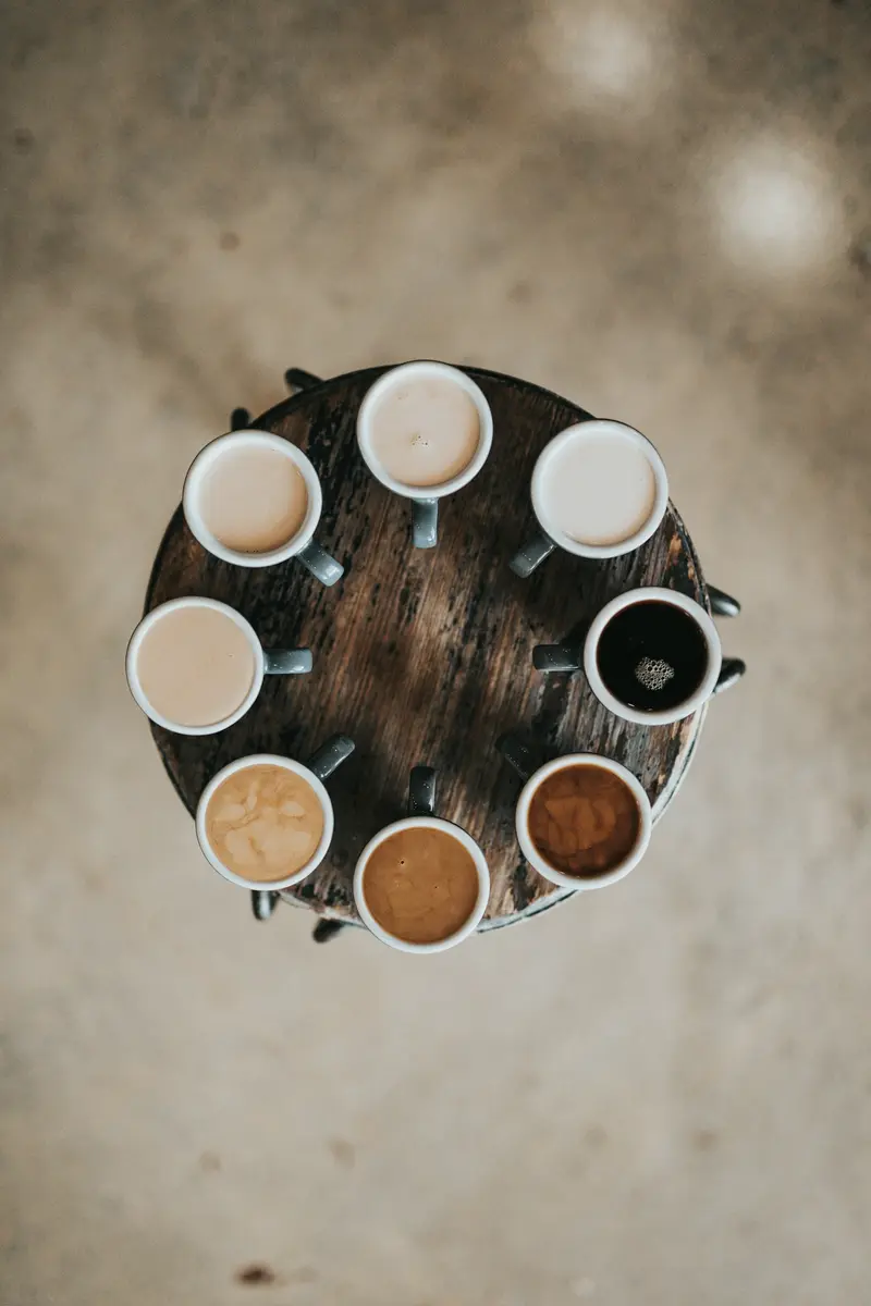 A circle of coffee cups seen from above on a wooden table