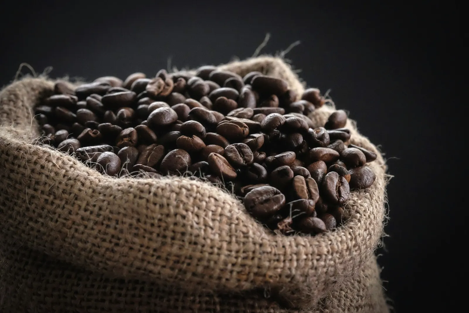 A burlap sack overflowing with roasted beans